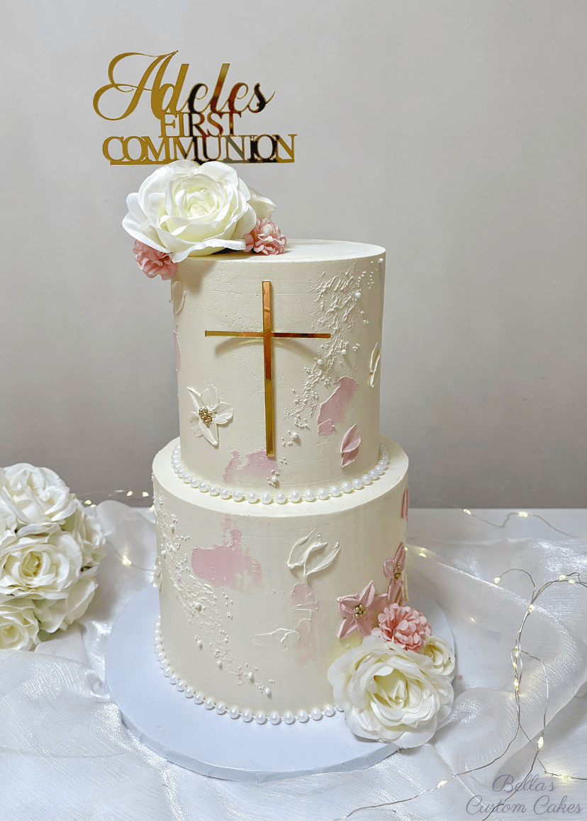 Two-tier white communion cake adorned with gold cross and pearl accents